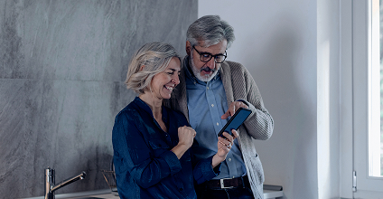 Elderly couple smiling while looking at a cell phone screen.